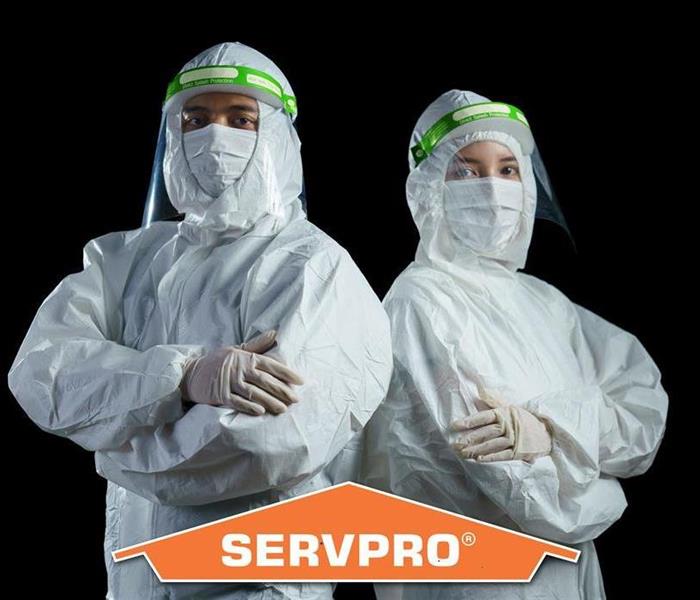 a man and woman in full personal protective equipment with a SERVPRO logo